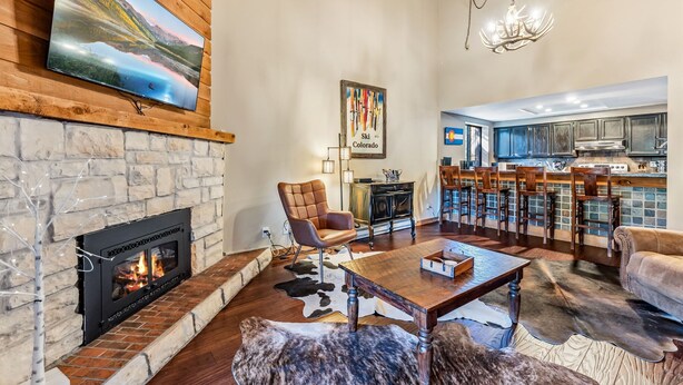 Una sala de estar con chimenea, televisión y una cocina al fondo.