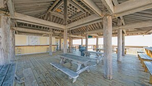 A wooden deck with picnic tables and a covered area with a wooden ceiling and beams. - Free Beach Service Canal Views! Pet Friendly! Sandpiper Cove 4103! (Destin)
