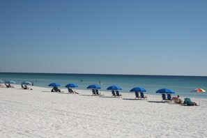 A beach with rows of blue umbrellas and beach chairs. - Budget Friendly 2Bd Beachfront with $1000000 View! Seasonal Beach Service! (Fort Walton Beach)