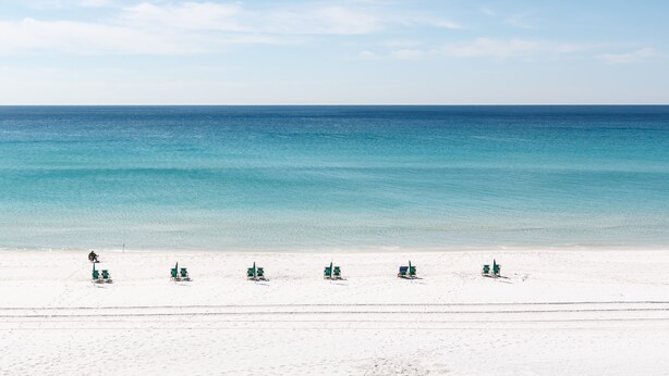 A beach with white sand and a clear blue sea. There are several green lounge chairs aligned in a row. - Budget Friendly 2Bd Beachfront with $1000000 View! Seasonal Beach Service! (Fort Walton Beach)