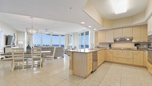 A spacious kitchen with a large island, modern appliances, and a view of the ocean.