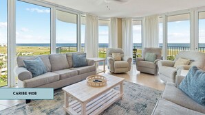 A spacious living room with a large window overlooking a scenic view, a ceiling fan, and a light-colored coffee table.