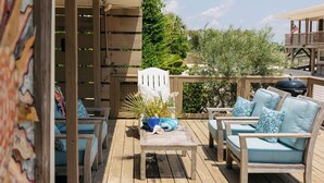 Una terraza de madera con mobiliario exterior, incluyendo un sofá y sillas, además de una mesa con adornos.