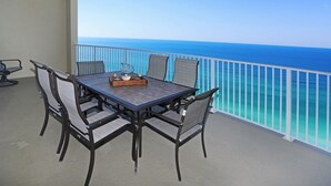 A balcony with a table and chairs, overlooking a clear blue ocean.