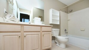 A bathroom with a beige vanity, white toilet, and bathtub.