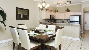 A dining area with a wooden table, white chairs, and a chandelier.