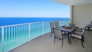 A balcony with a table and chairs, overlooking a clear blue sea.