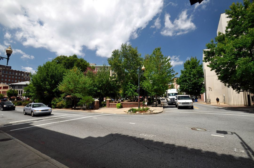 A city street with cars, trees, and buildings.
