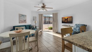 A dining area with a round table, chairs, and a view of the outside. - Gulfview II 101 | Ground Floor • 100 Steps to Beach • Free Beach Service • Sleep (Destin)
