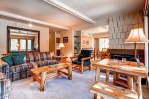 A cozy living room with a plaid sofa, wooden coffee table, and a fireplace.
