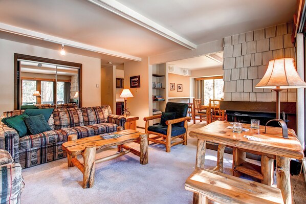 Una sala de estar acogedora con un sofá a cuadros, una mesa de centro de madera y una chimenea.