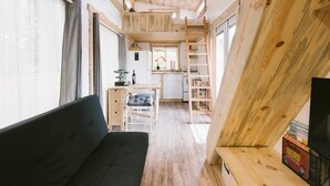 A compact, wooden interior with a sofa, a small desk, and a kitchen area. - Modern Cozy Urban Tiny House near Airport and Transportation-Private Setting (Des Moines)