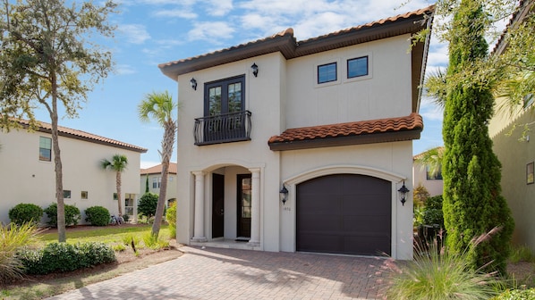 A two-story house with a balcony, a garage, and a well-maintained garden.