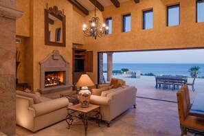 A spacious living area with a fireplace, comfortable seating, and a view of the ocean. - Oceanfront Villa Steps to Golf w/ Pool, Hot Tub & Sea of Cortez Views Cabo (Turistico Correder)