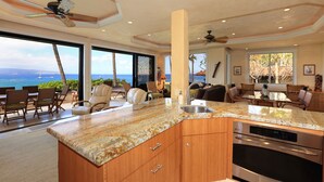 Una cocina amplia con una isla grande, horno empotrado y vista al océano.