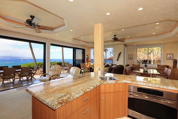 A spacious kitchen with a large island, built-in oven, and a view of the ocean.