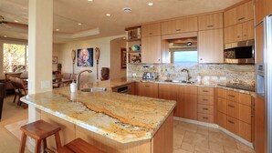 Una cocina moderna con gabinetes de madera, encimeras de granito y electrodomésticos de acero inoxidable.