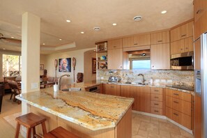 A modern kitchen with wooden cabinets, granite countertops, and stainless steel appliances.