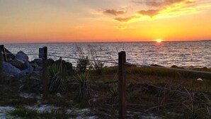 Un atardecer sobre una playa con una cerca y rocas al frente.