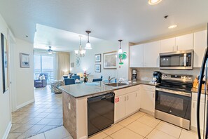 A modern kitchen with a central island, stainless steel appliances, and a dining area with blue chairs.