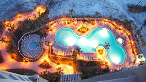 An aerial view of a resort with a large, winding pool surrounded by palm trees and lounge areas. - Paradise Harbor Grand Panama PCB-Beachfront 2Bd+Bunks-2Ba-Pet Friendly (Panama City Beach)