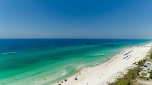 A beach with a pier extending into the ocean, sandy beach, and beach umbrellas. - Paradise Harbor Grand Panama PCB-Beachfront 2Bd+Bunks-2Ba-Pet Friendly (Panama City Beach)