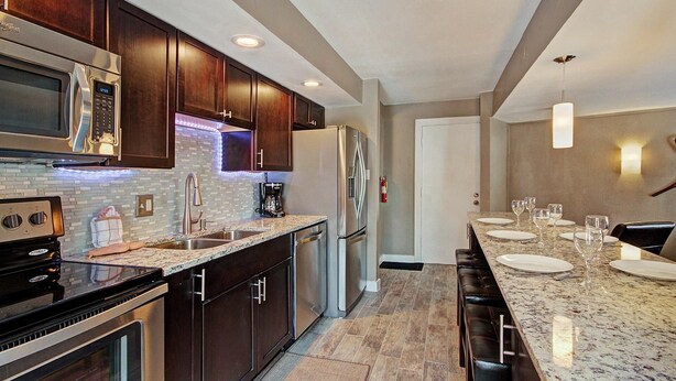 A modern kitchen with dark wood cabinets, stainless steel appliances, and a marble countertop. - Free SkyCard Activities - Remodeled, Close to Peak 8 - Peak 8 Village E35 (Breckenridge)