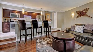 A modern kitchen with dark wood cabinets, stainless steel appliances, and a bar area with stools. - Free SkyCard Activities - Remodeled, Close to Peak 8 - Peak 8 Village E35 (Breckenridge)