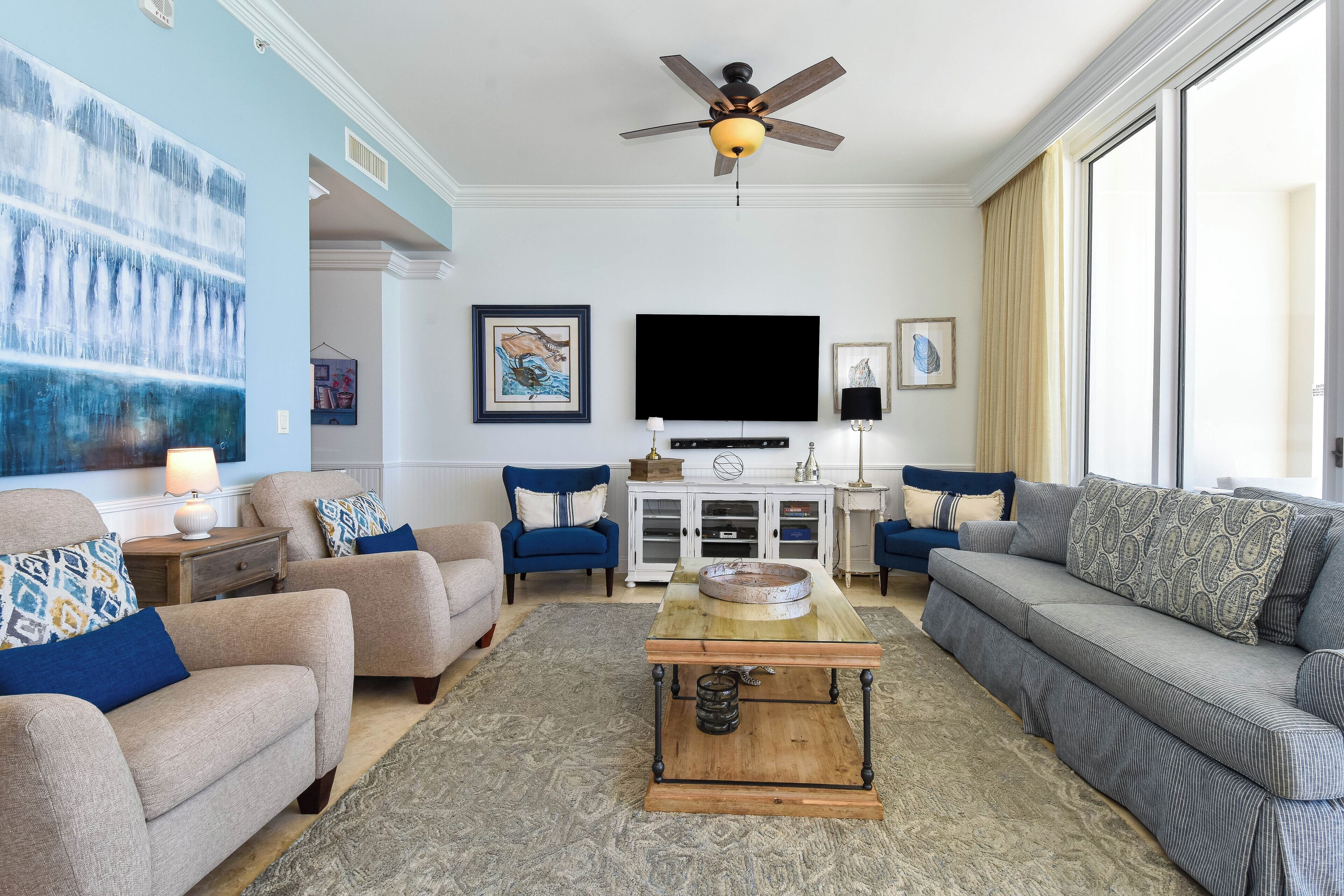A living room with a sofa, armchairs, a coffee table, a TV, and artwork on the walls.