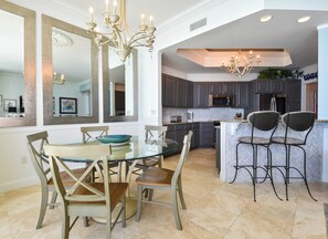 A modern kitchen with dark cabinets, a glass dining table, and a bar area.