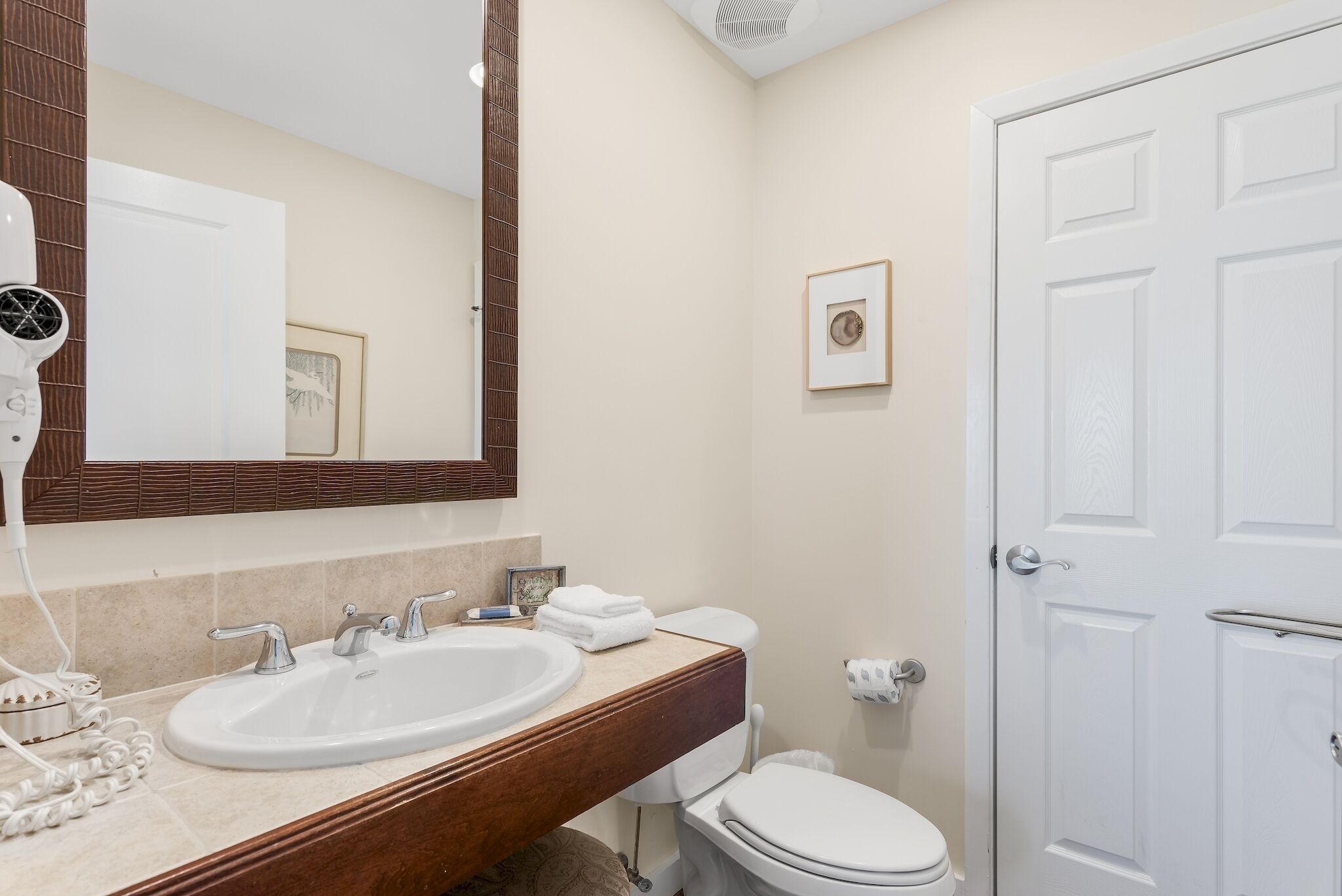 A bathroom with a white sink, a mirror, a toilet, and a white door.