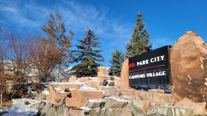 Señal de Park City Canyons Village con cielo despejado y suelo cubierto de nieve.