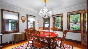 A dining room with a wooden table, chairs, a chandelier, and large windows. - Beautiful Cheyenne Cañon Retreat with Hot Tub, Walk To Broadmoor Hotel & Trails. (Colorado Springs)