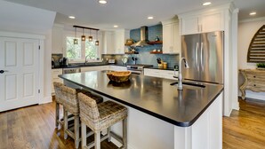 Una cocina moderna con una isla central, electrodomésticos de acero inoxidable y armarios blancos.