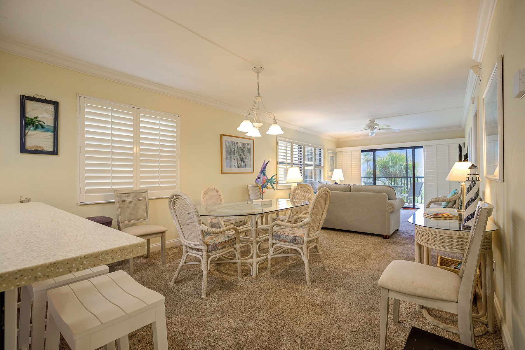 A spacious living area with a dining table, chairs, a sofa, and a balcony with a view.