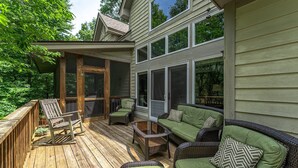 Une terrasse en bois avec des meubles en osier et une table basse en verre.