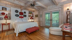 Une chambre avec un plafond en bois, un lit avec un banc rouge, une table de chevet et une table avec une lampe.