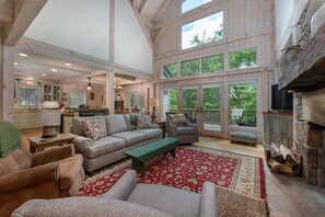 Relax in this spacious living area with a high ceiling, comfortable sofa set, and large windows offering views of the surrounding greenery.