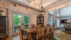 Une salle à manger en bois avec une grande table et des chaises, un lustre et une bibliothèque.