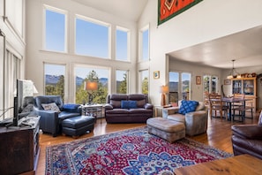 Relax in this stylish living room with a high ceiling, large windows, and a comfortable seating area.