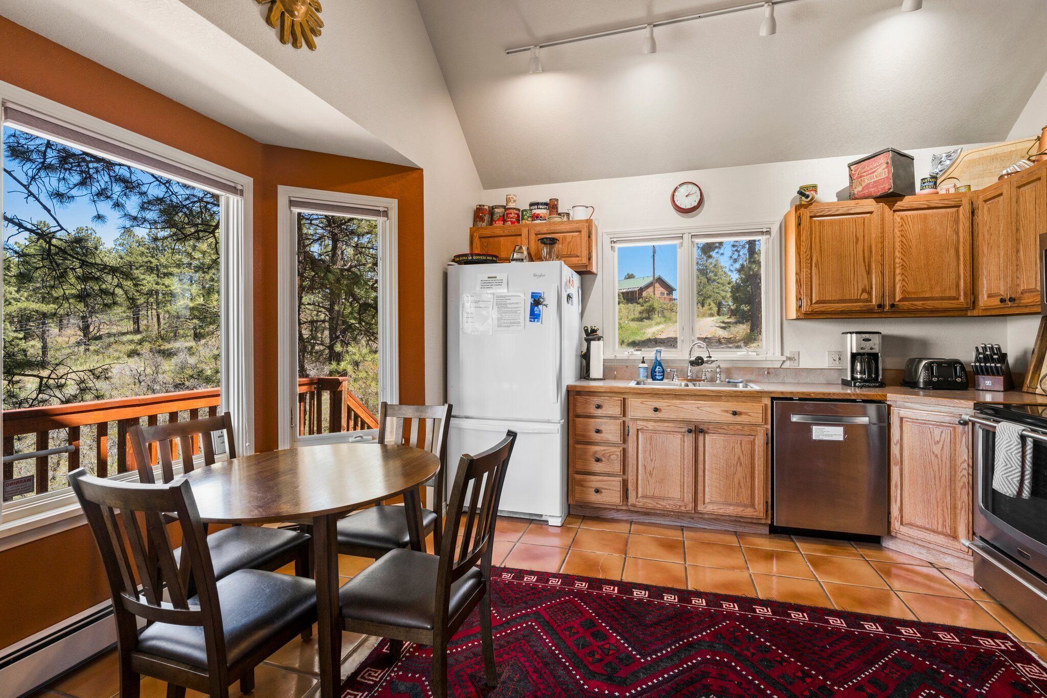 A kitchen with wooden cabinets, a refrigerator, a sink, and a dining area with a table and chairs.