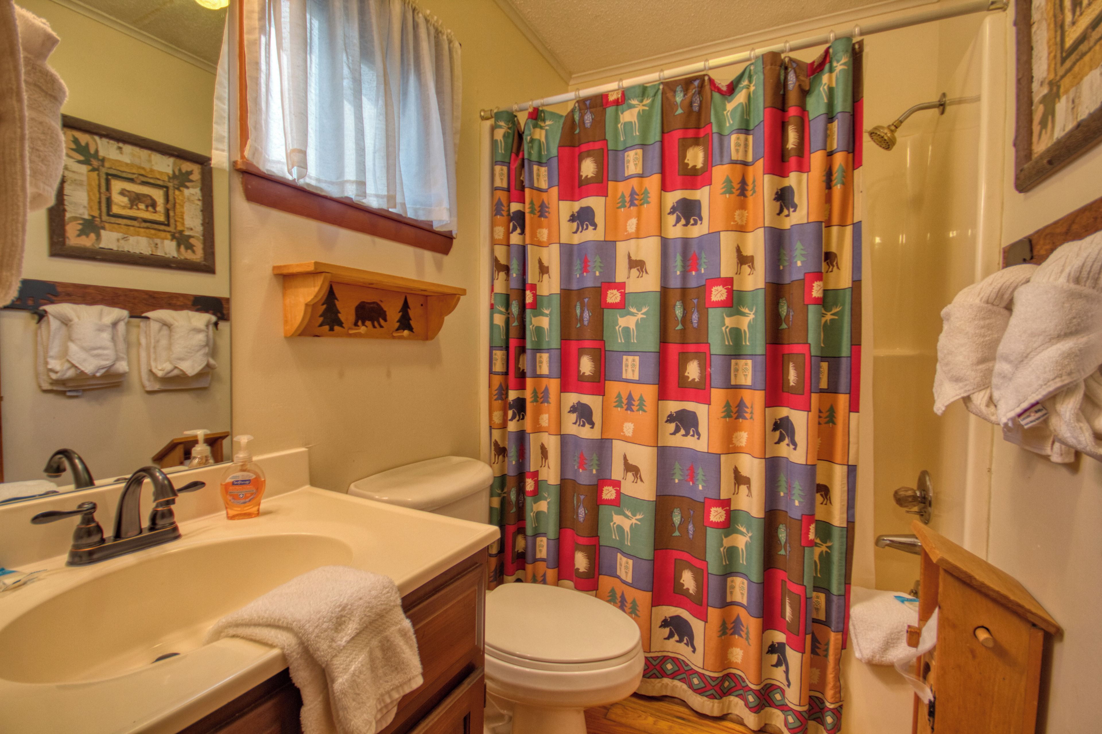 A bathroom with a sink, toilet, and shower curtain with animal prints.