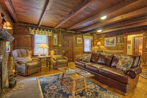 A cozy, rustic interior with a leather sofa, wooden furniture, and a fireplace.