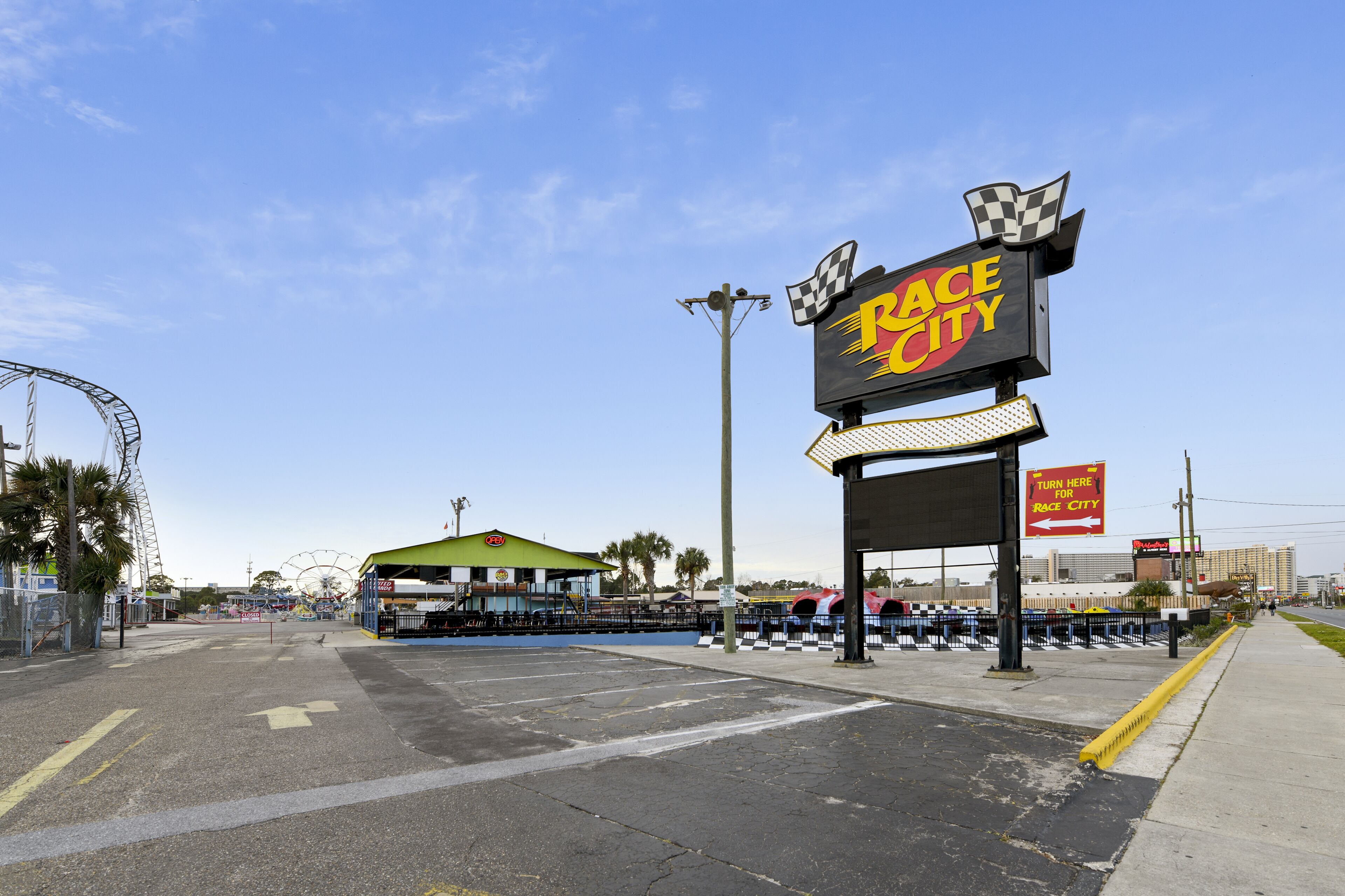 A parking lot with a sign for "Race City" and a Ferris wheel in the background.