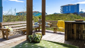 Eine Holzterrasse mit Bänken und einem Tisch, die auf einen Hang mit Gebäuden blickt.