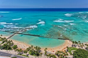 Una playa con aguas turquesas cristalinas, un muelle de madera y palmeras.