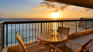 A balcony with a round table and chairs, overlooking a sunset over the ocean. - Spectacular Diamond Head and Ocean Views! Free Valet Parking, Wi-Fi, Pool! (Honolulu)