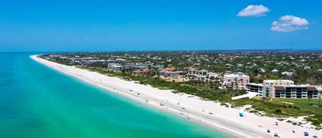A coastal resort with a long sandy beach, beachfront villas, and a clear view of the ocean.