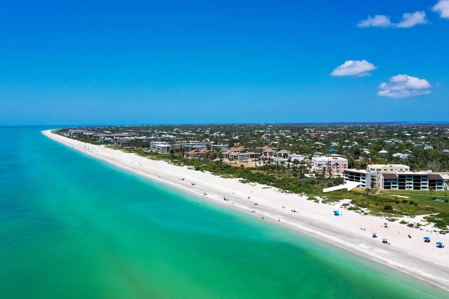 A coastal resort with a long sandy beach, beachfront villas, and a clear view of the ocean.
