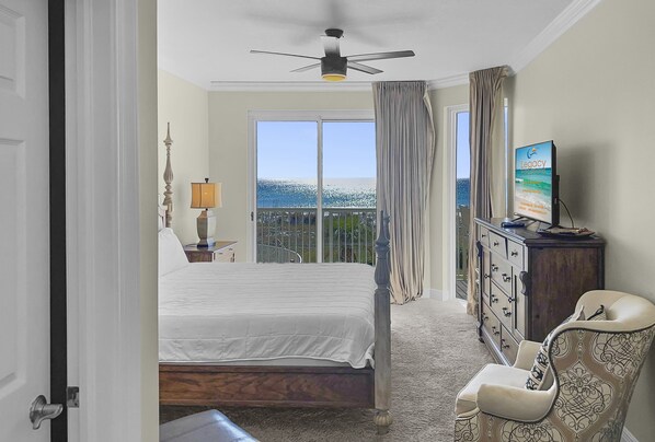 Une chambre d’hôtel avec un lit, une chaise, une commode, une télévision et un balcon avec vue.
